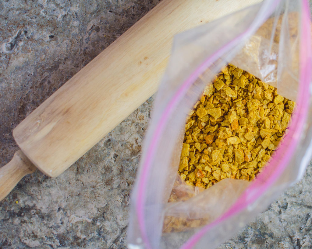 Rolling pin next to bag of crushed tortilla chips. 