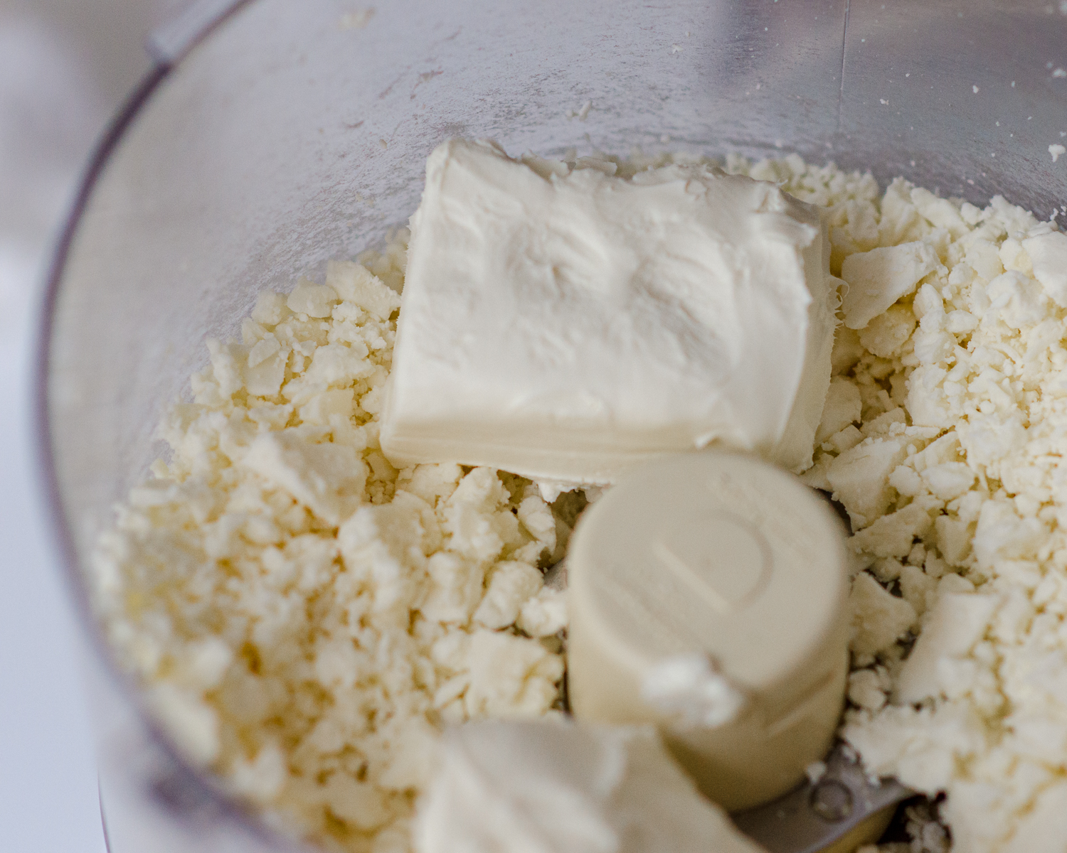 Feta cheese crumbles and cream cheese squares in the food processor. 
