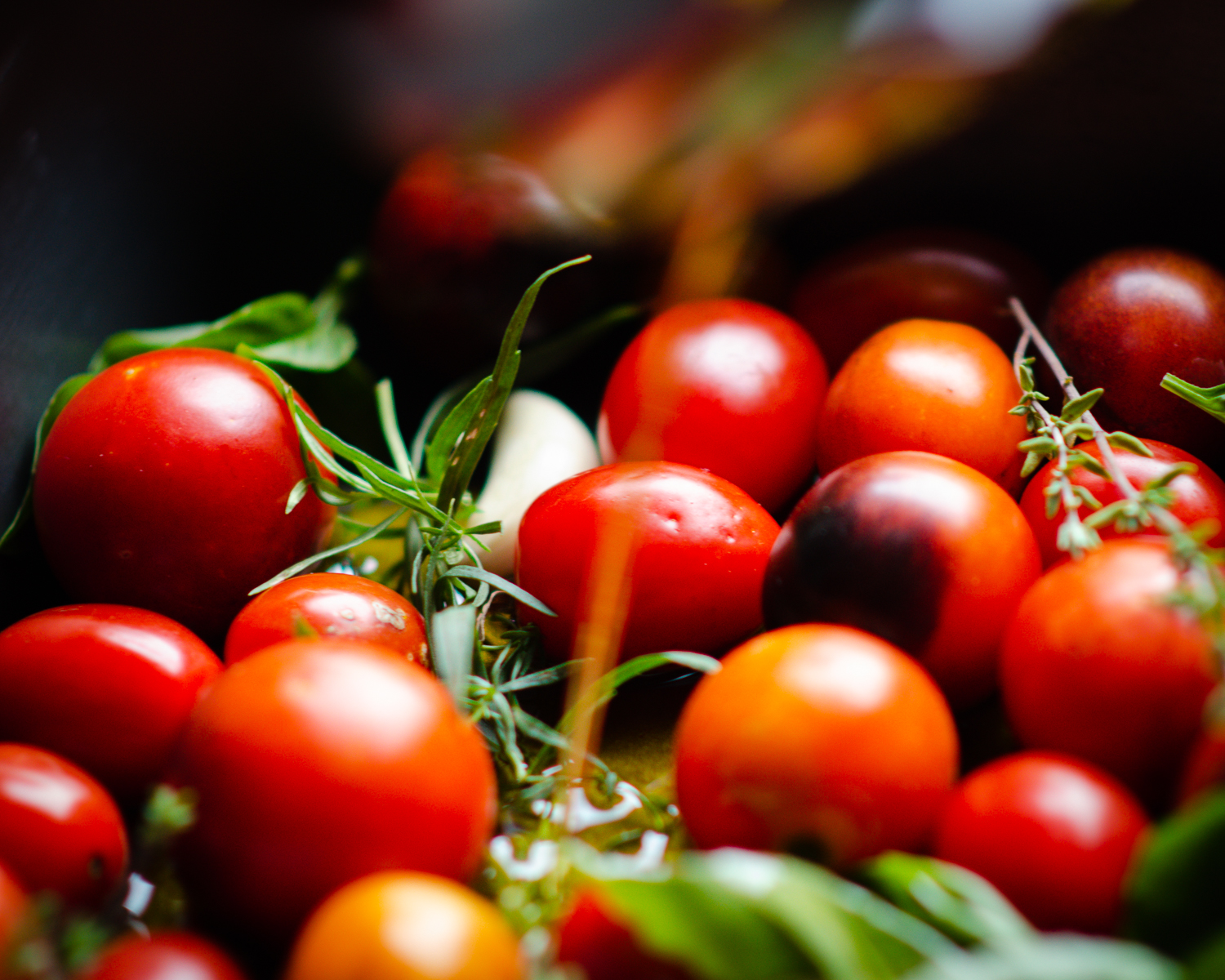 Oil being poured over tomatoes and herbs. 