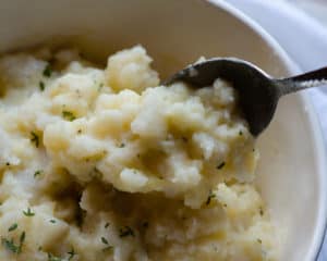 Buttery mashed turnips being spooned out of a bowl