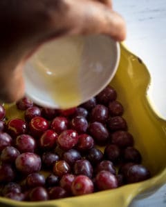 Hand pouring oil on grapes