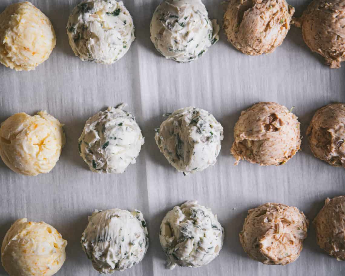 Round scoops of compound butters lined up on parchment paper.