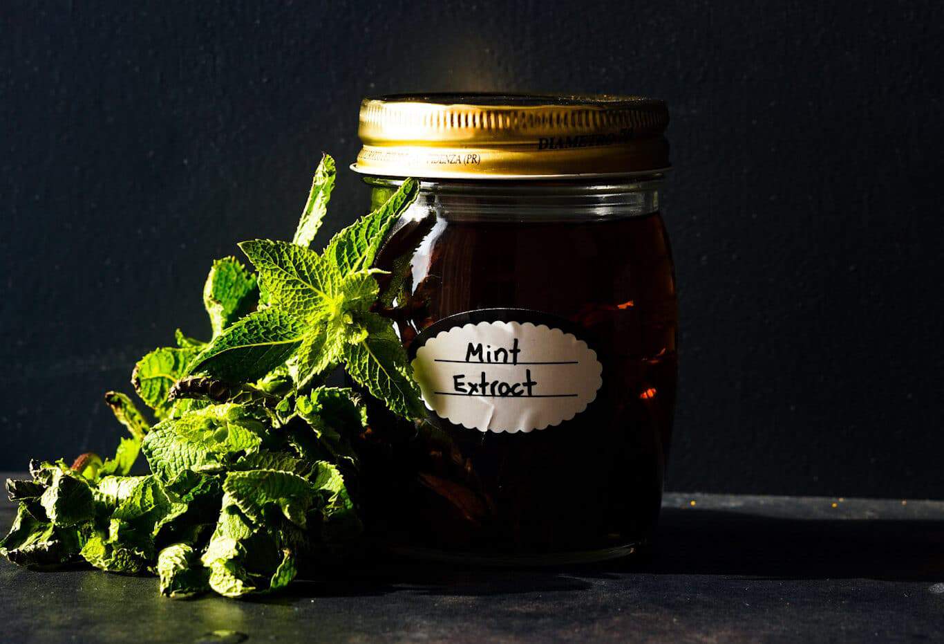 Mason jar labeled "Mint Extract" next to sprig of mint