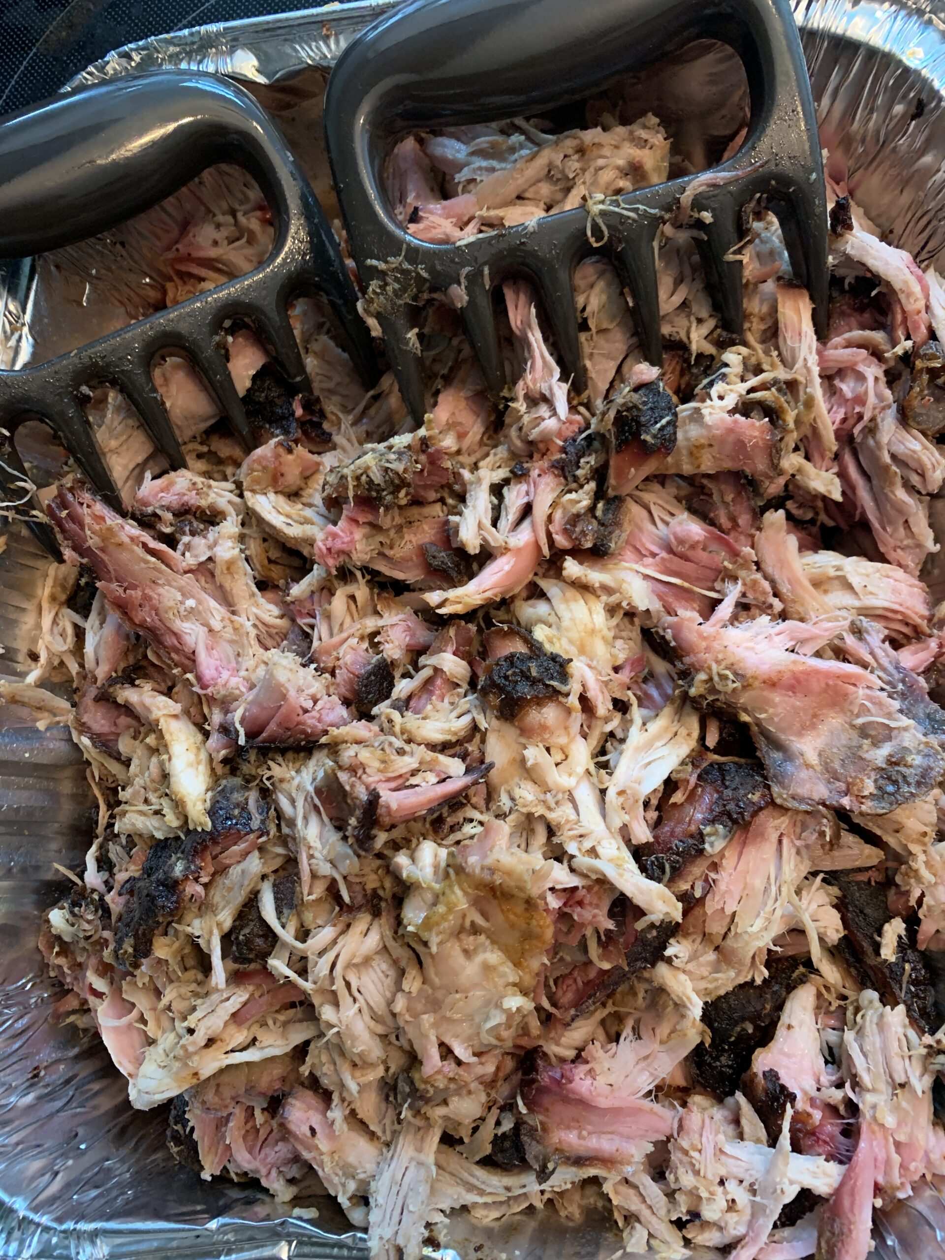 Pulled pork in foil pan with meat claws. 