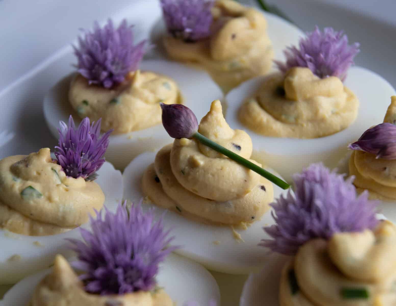 Chive and truffle deviled eggs garnished with purple chive blossoms.