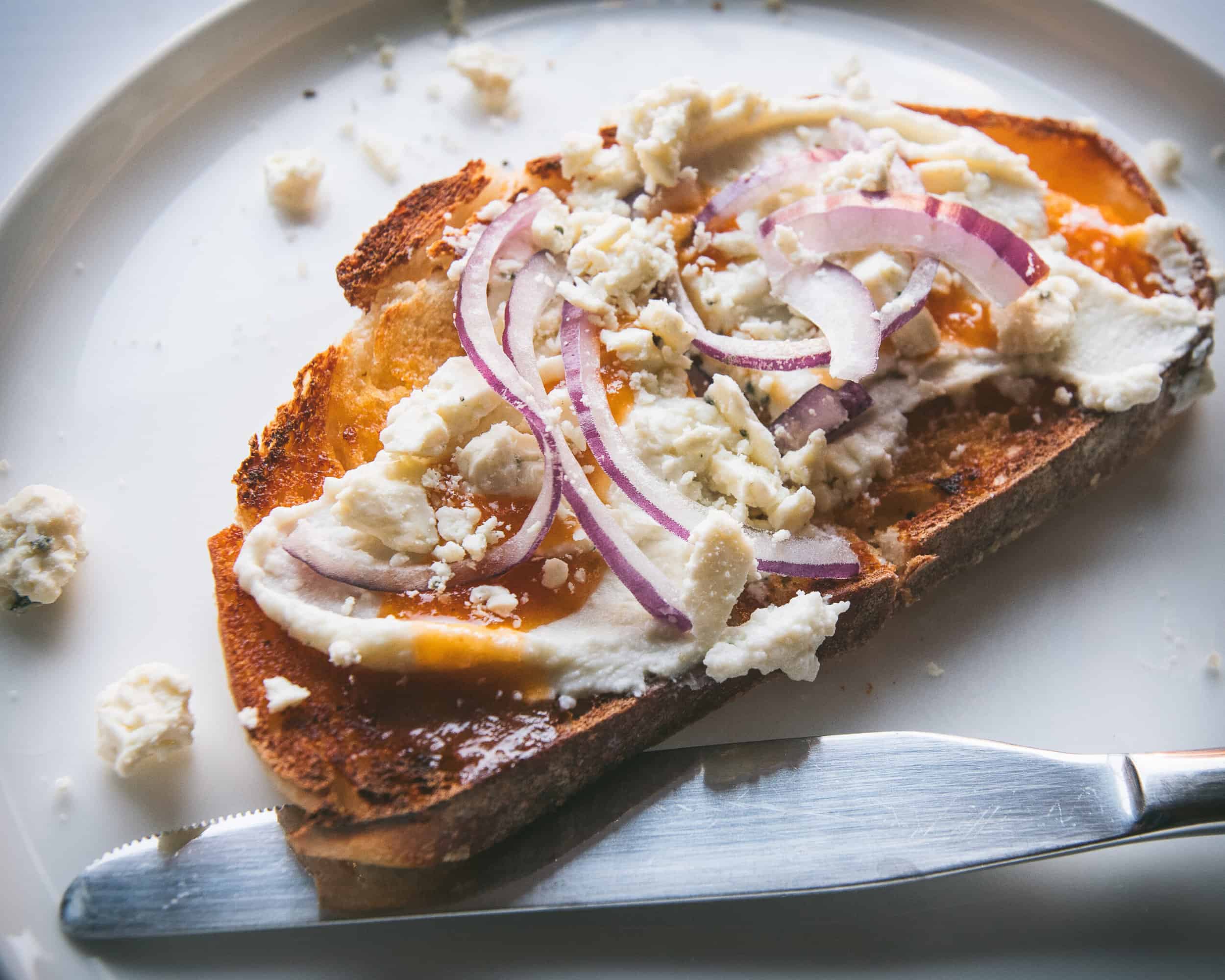 Toasted bread topped with buffalo sauce, whipped blue cheese spread and sliced red onions