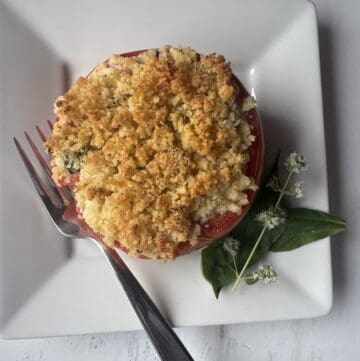 A white plate topped with a baked tomato.