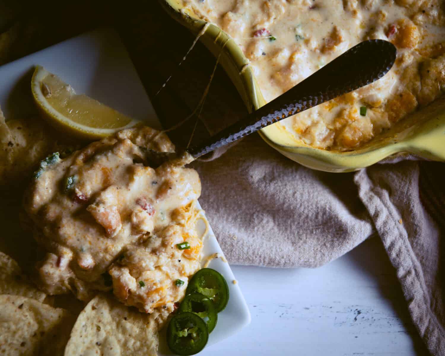Shrimp dip with pepper slices and lemon for garnish.