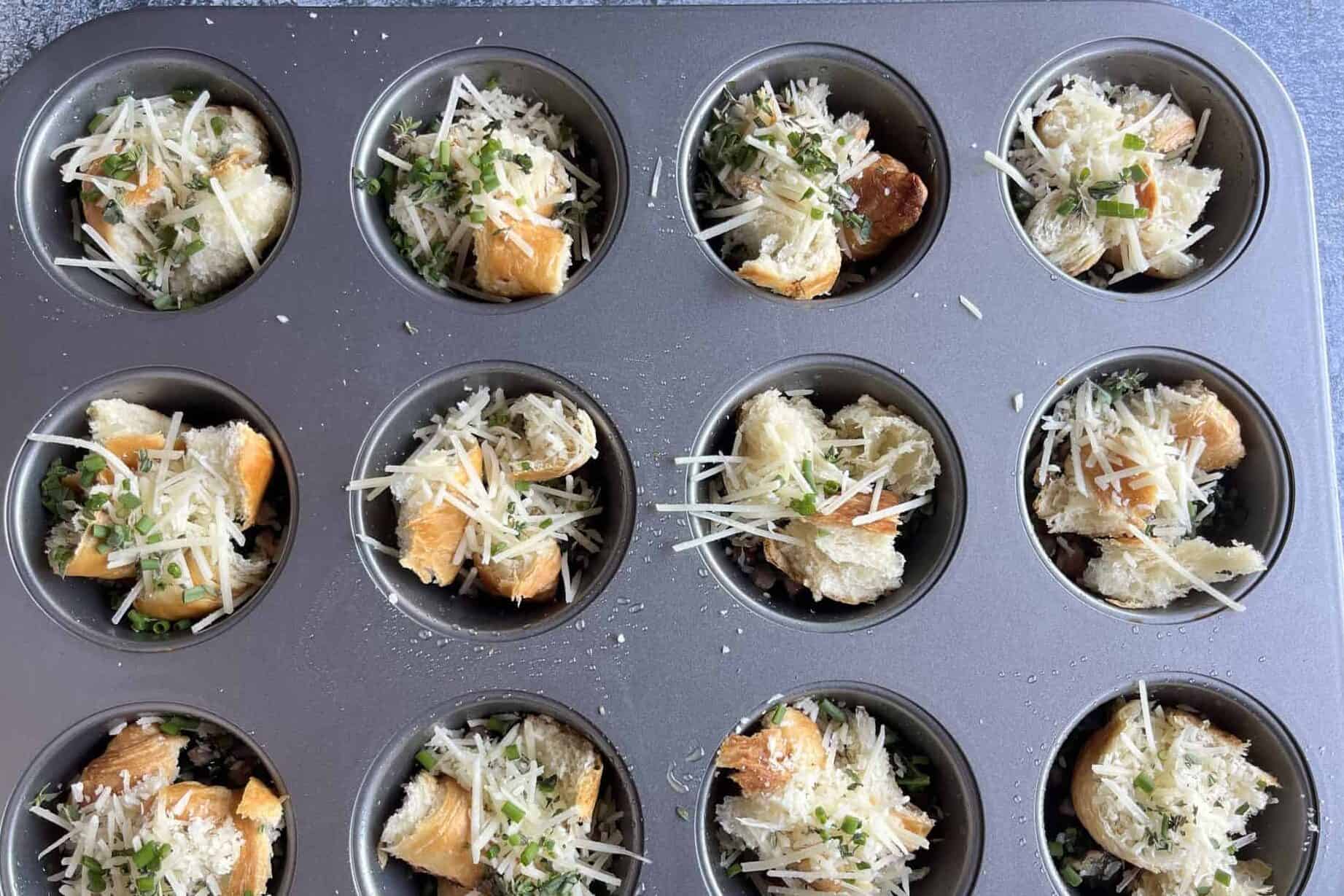 muffin tin with each cup filled with torn croissants, shredded cheese, herbs and pancetta mix to make savory croissant egg bites.