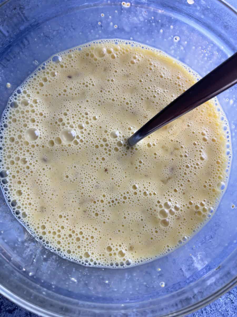 frothy egg mixture in a glass bowl with fork that was used to combine the ingredients.