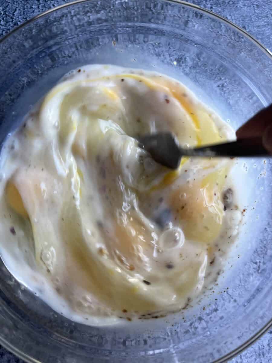 fork whisking egg mixture in a glass bowl.