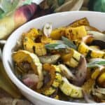 roasted delicata squash in a white serving bowl with a towel.