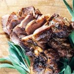 Slices of cider braised pork on a cutting board.