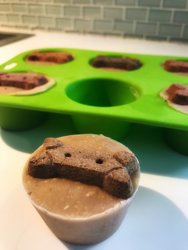 Frozen dog treats outside of a green siliconemuffin pan